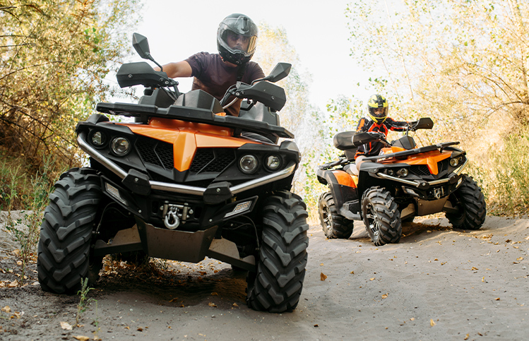 People riding UTVs in a wooded area